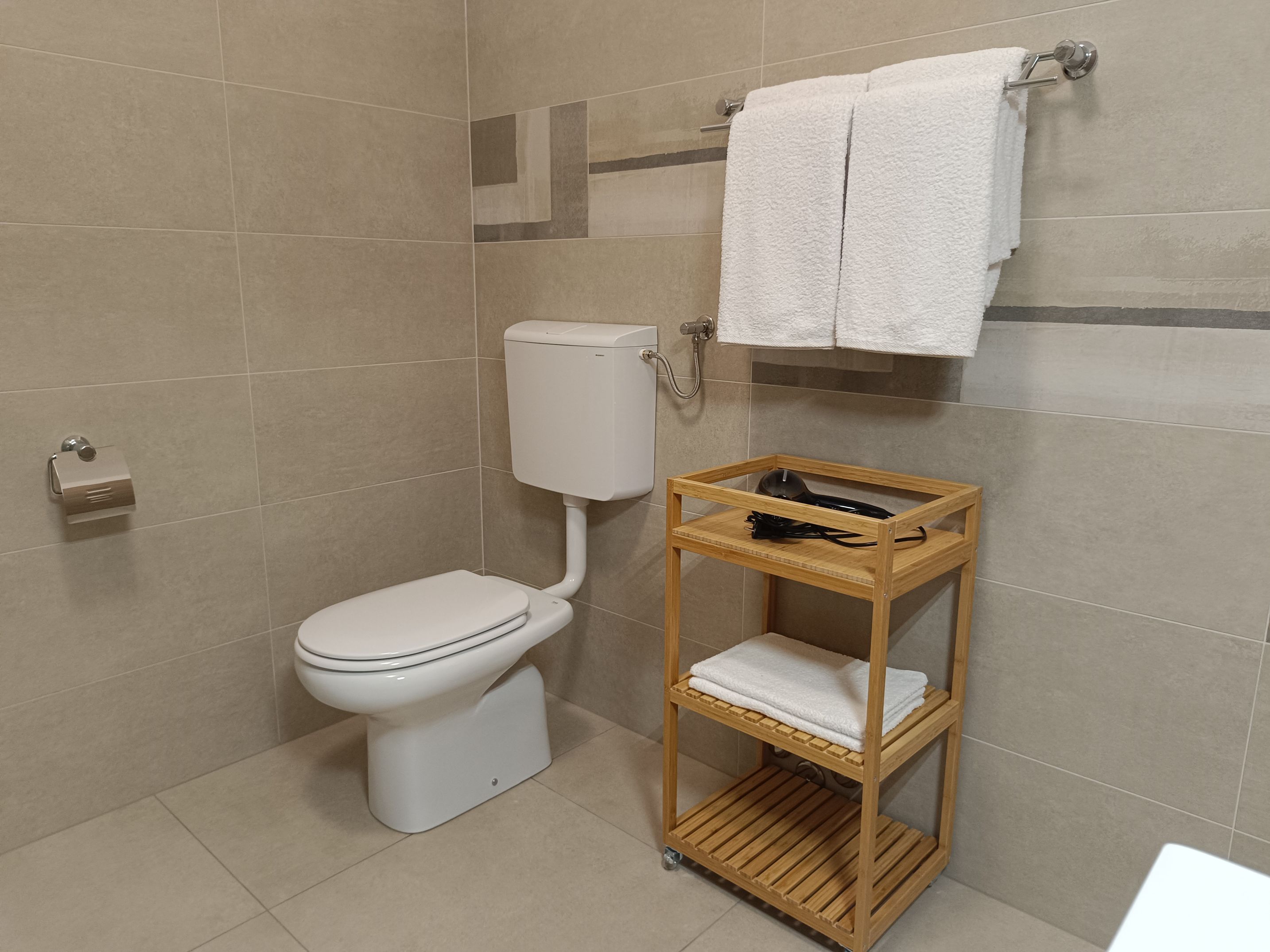 Elegant dining table and chairs in dining room with cutlery. Fridge and microwave. Spacious living room which contains a couch, coffee table, TV and cupboards. Entrance of the apartment that includes a shelf, mirror, cupboard and cabinet.