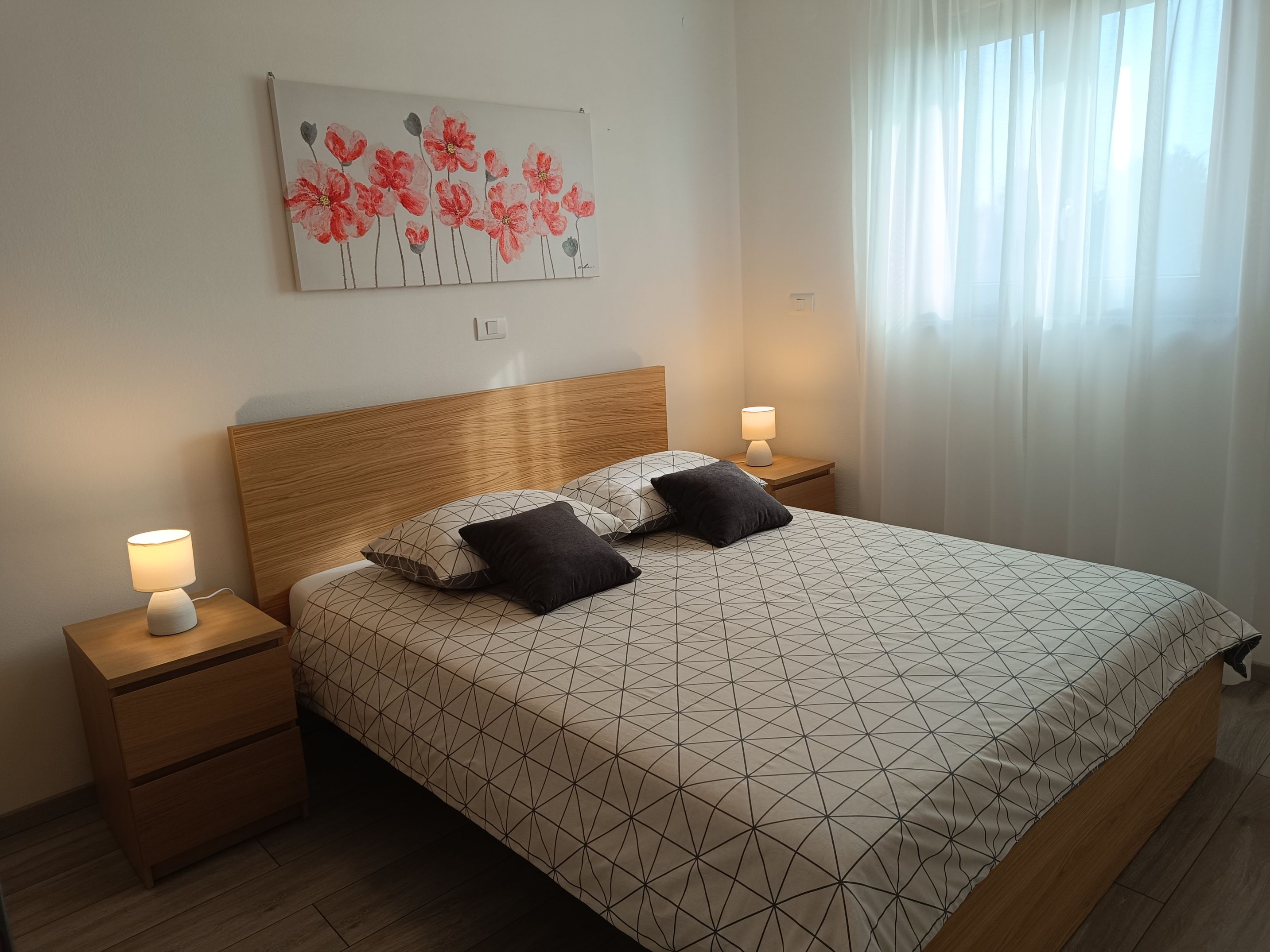 Big spacious tiled bright bathroom with appliances. Mirror above the sink with cupboards. Washing machine under the boiler. Towels in different colors on the hangers and on the towel shelf. Hair dryer on the shelf. Additional hangers on the wall.